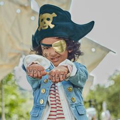 a young boy wearing a pirate hat and pointing at the camera with his hands in front of him