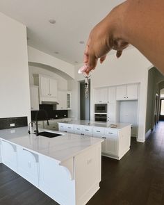 a hand is holding a key to a kitchen with white cabinets and an island in the middle