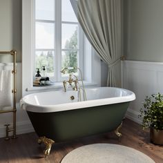 a bathroom with a claw foot bathtub, rugs and windows in the background