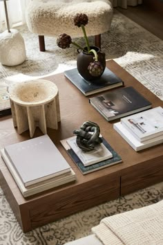 a wooden table topped with books and a vase filled with flowers on top of it