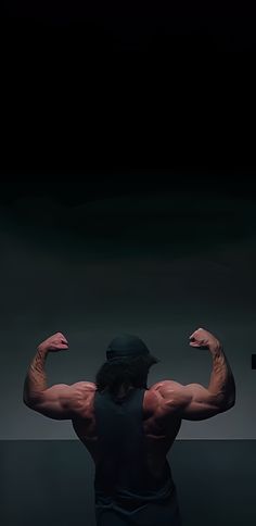 a man flexing his muscles in the dark