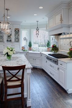 a large kitchen with white cabinets and marble counter tops, along with an island in the middle