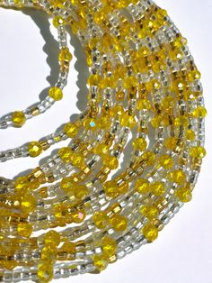 Single Strand Waist Bead "Lagunes" features a single strand adorned with clear glass beads, harmoniously complemented by radiant yellow and deep blue larger crystal glass bead accents. Immerse yourself in the celestial glow of this waist bead, designed to adorn your silhouette with a touch of cosmic elegance. 💎 Clear Glass Beads - Clarity and Radiance: The single strand begins with clear glass beads, symbolizing clarity and radiance. Clear hues evoke a sense of transparency, allowing your inner Clear Faceted Round Beads Jewelry, Yellow Multi-strand Polished Beads Jewelry, Yellow Multi-strand Jewelry With Polished Beads, Yellow Jewelry With Polished Oval Beads, Yellow Glass Beaded Necklace, Yellow Oval Polished Bead Jewelry, Spiritual Beaded Clear Jewelry, Spiritual Yellow Jewelry With Gold Beads, Spiritual Clear Beaded Jewelry