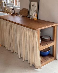 a kitchen with a sink and wooden counter top next to an open shelf on the wall