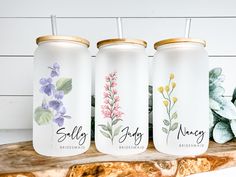 three personalized tumblers with flowers on them sitting next to a succulent plant