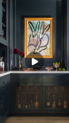 a kitchen with blue walls, cabinets and an art work on the wall above it