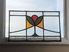 a close up of a stained glass window with sky in the back ground behind it