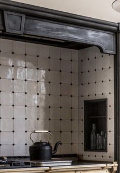 a kitchen with a stove top oven sitting next to a wall covered in black and white tiles