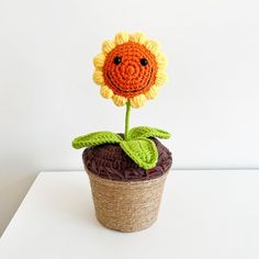 a crocheted sunflower sitting on top of a brown pot filled with grass