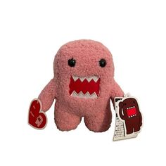 a pink stuffed animal with big teeth holding a red heart shaped sticker on it's chest