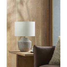 a table lamp sitting on top of a wooden table next to a brown leather chair