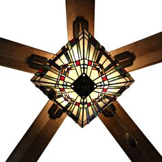 a stained glass light hanging from the ceiling in a room with wooden beams and cross legs