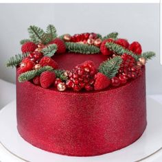 a red cake decorated with berries and greenery