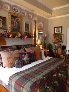 a bed with many pillows and pictures on the wall next to it in a bedroom