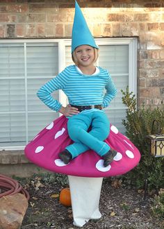 a child in a costume sitting on top of a mushroom