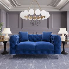 a blue couch sitting in a living room next to two lamps and a chandelier