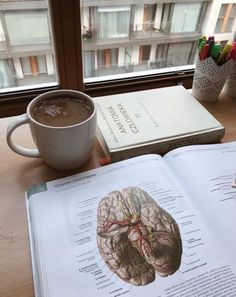 a cup of coffee and an open book on a table