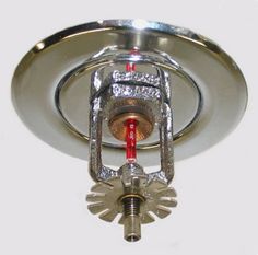 a close up of a light fixture on a white wall with a red light in the middle