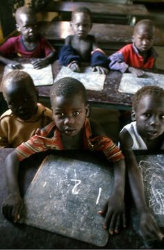 several children are sitting at a table with chalk on it and numbers written on them