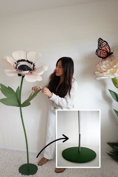 a woman standing next to a fake flower