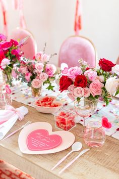 the table is set for valentine's day with pink and red flowers