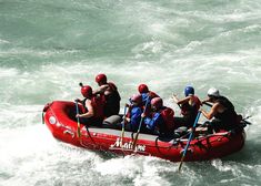 a group of people riding on the back of a red raft in rough white water