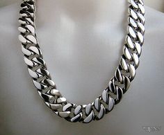 Formal Silver Stainless Steel Necklaces, Silver Cuban Link Jewelry With Sterling Clasp, Luxury Stainless Steel Necklace With Silver Chain, Designer Sterling Silver Jewelry With Silver Chain, Designer Silver Chain Jewelry, Luxury Silver Metal Necklace, Luxury Engraved Silver Chain Necklace, Luxury Sterling Silver Curb Chain Jewelry, Silver Engraved Cuban Link Necklace