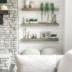 a living room filled with white furniture and lots of greenery on top of shelves