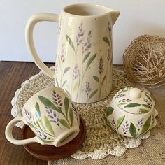 a pitcher and two cups on a doily with some twine in the background