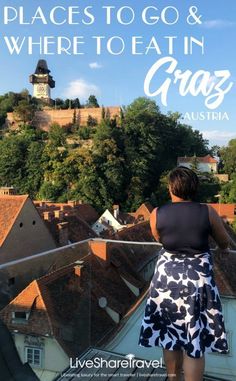 a woman standing on top of a roof looking out at the city and hills behind her