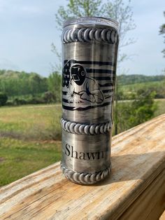 a shot glass sitting on top of a wooden table in front of a grassy field