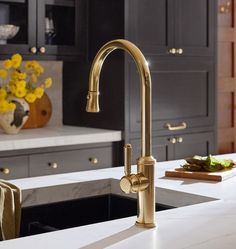 a golden faucet is on the counter in a kitchen with black cabinets and yellow flowers