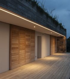 an empty room with wooden flooring and lights on the side of the building at night