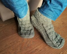 a person standing on the floor with their feet up wearing slippers that are crocheted