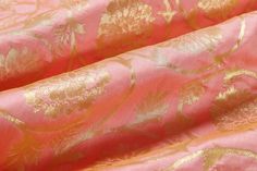 pink and gold brocaded fabric with golden floral designs on the reverse, close up