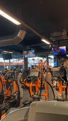 there are many treadmills in the gym with orange and black accents on them