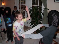 a group of kids standing around each other in a living room with their arms up