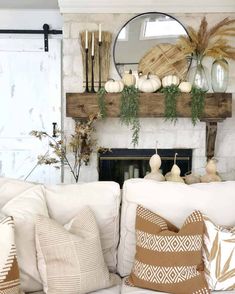 a living room filled with lots of white furniture and decor on top of a fireplace