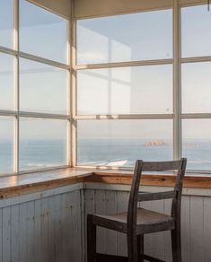 a chair sitting in front of a window overlooking the ocean