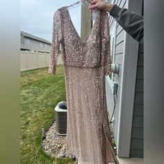 a woman holding onto a dress hanging on a clothes line in front of a house