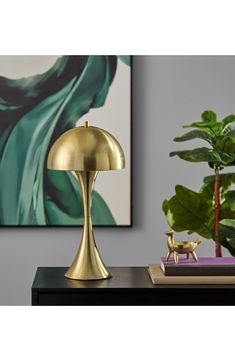 a gold lamp sitting on top of a wooden table next to a potted plant