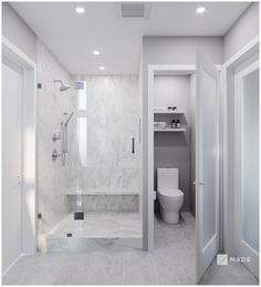 a white bathroom with marble floors and walls