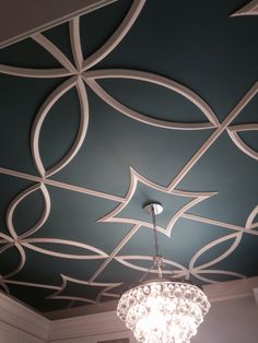 a chandelier hanging from the ceiling in a room with blue walls and white trim