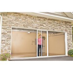 a woman standing in front of a garage door with her hands on the glass doors