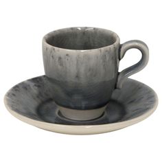 a cup and saucer sitting on top of a white plate with black glaze