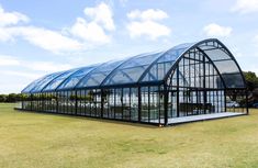 a large glass building sitting on top of a lush green field