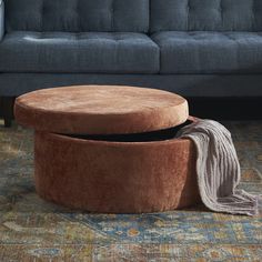 a round ottoman sitting on top of a rug next to a couch