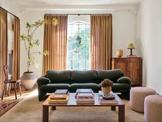 a living room filled with furniture and a large window covered in draping next to a wooden coffee table