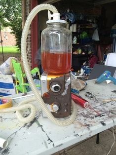 a table topped with lots of clutter next to a bottle filled with red liquid