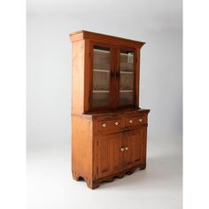 an old wooden china cabinet with glass doors and knobs on the front, against a white background